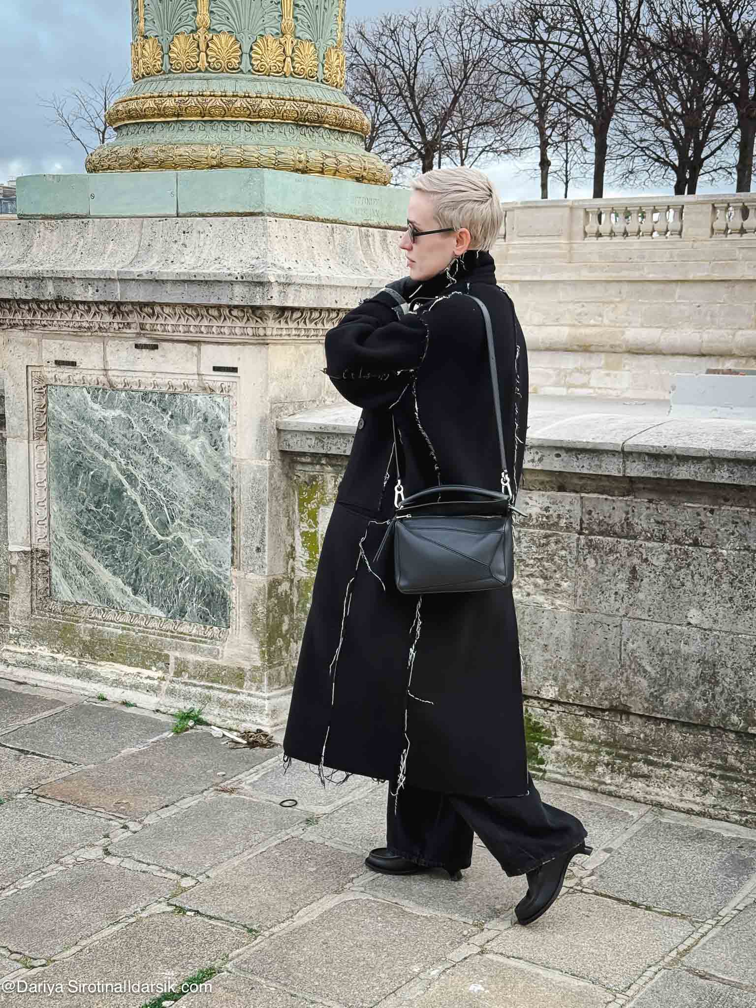 Парижский зимний образ: пальто Balenciaga, джинсы, лоферы Loewe со скошенным каблуком. Пример сочетания сдержанных цветов с интересной деталью.