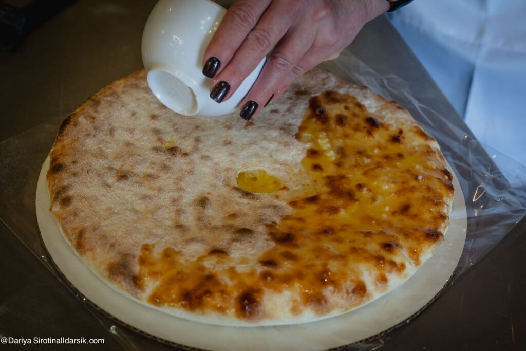 Подача осетинского пирога — горячий, нарезанный на 8 частей, с топлёным маслом, едят руками