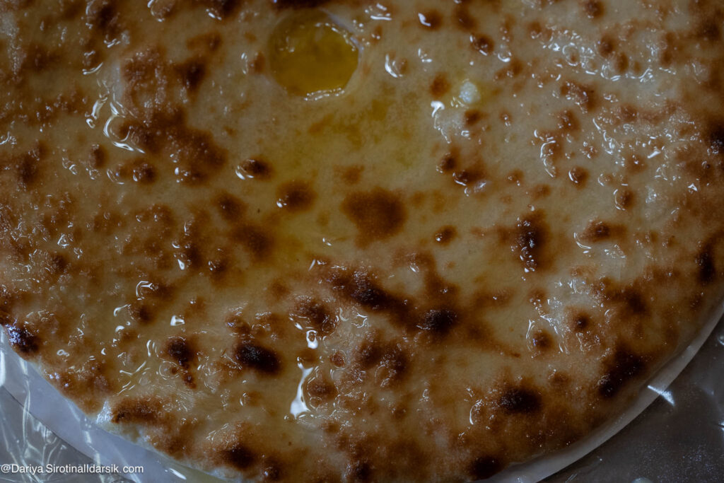 Подача осетинского пирога — горячий, нарезанный на 8 частей, с топлёным маслом, едят руками