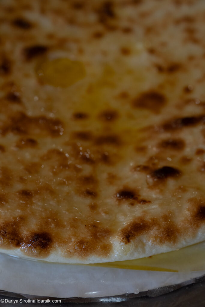 Подача осетинского пирога — горячий, нарезанный на 8 частей, с топлёным маслом, едят руками