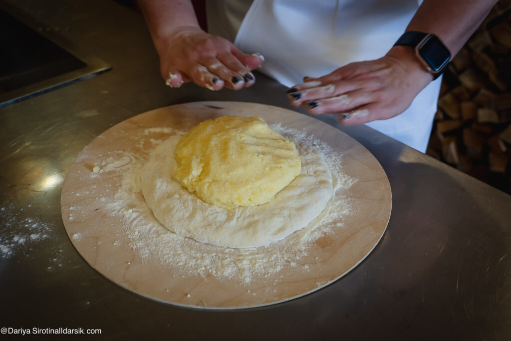 Мастер-класс по приготовлению осетинских пирогов в Хидикус-ауле, хозяйка раскатывает тесто руками без скалки